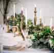 Gold goblets and candlesticks with green floral table decorations