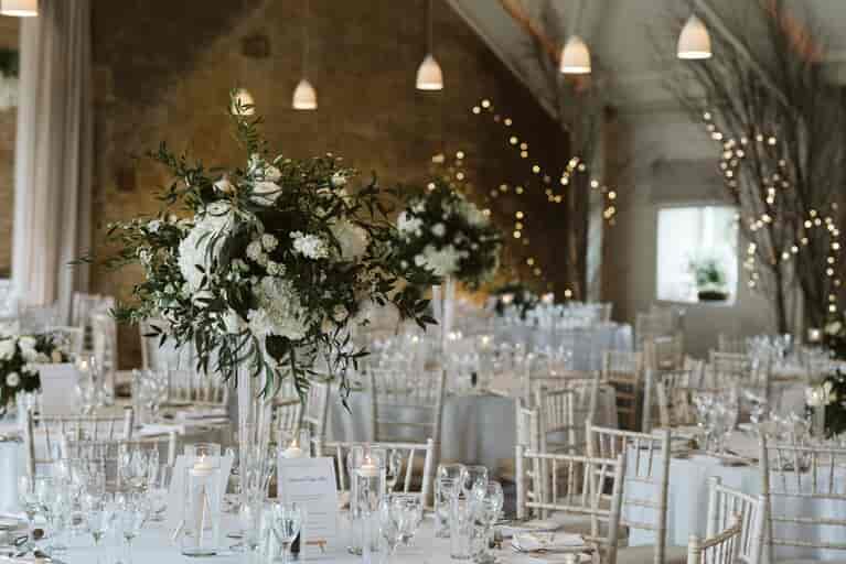 Tall vases of flowers decorate the dining tables. Photography by David Hughes Photography