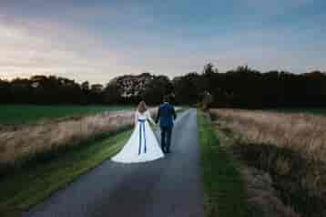 Bride and groom walking down the drive together. Image by Tanli Joy Photography