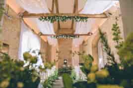 Cotswold barn dressed for a wedding ceremony with drapes and hanging flowers